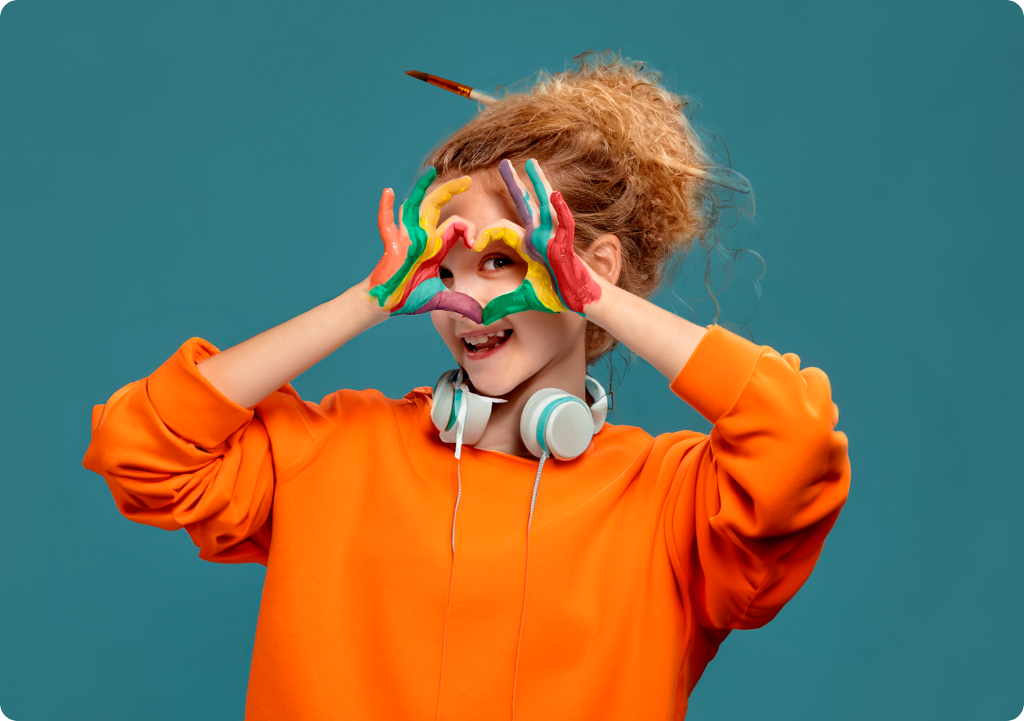 Fun kid shaping a heart with her hands painted in various colours. Represents inclusivity and harmonious comunities. Sustainable Vacation Rental Awards